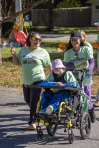 Two women walking and pushing a child in a wheelchair at a Walk & Roll event.